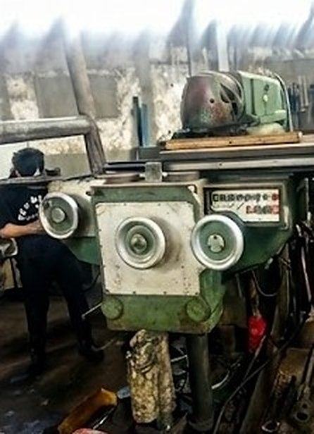 Vista frontal de la fresadora con su panel de mandos y volantes, con un operario al costado