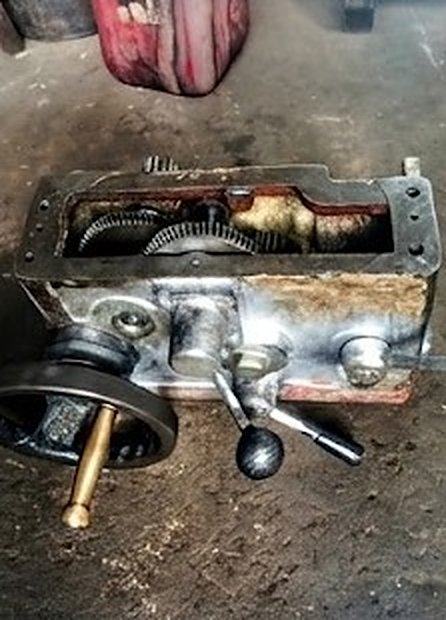 Caja de engranajes extraída de la fresadora, con volante y palanca de mando, sobre el piso del taller